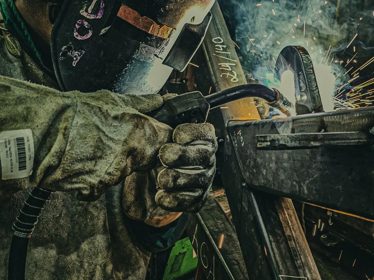 A welder joining a steel frame with a MIG torch
