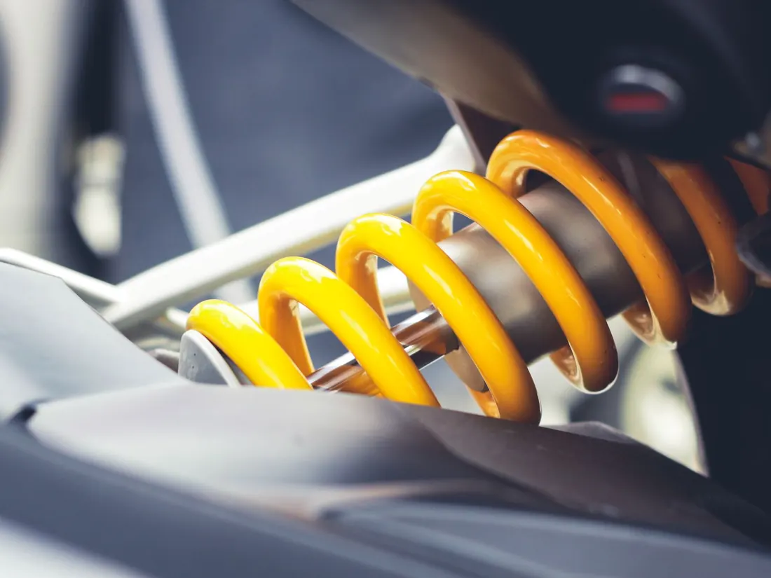 A yellow coil spring on a vehicle suspension unit