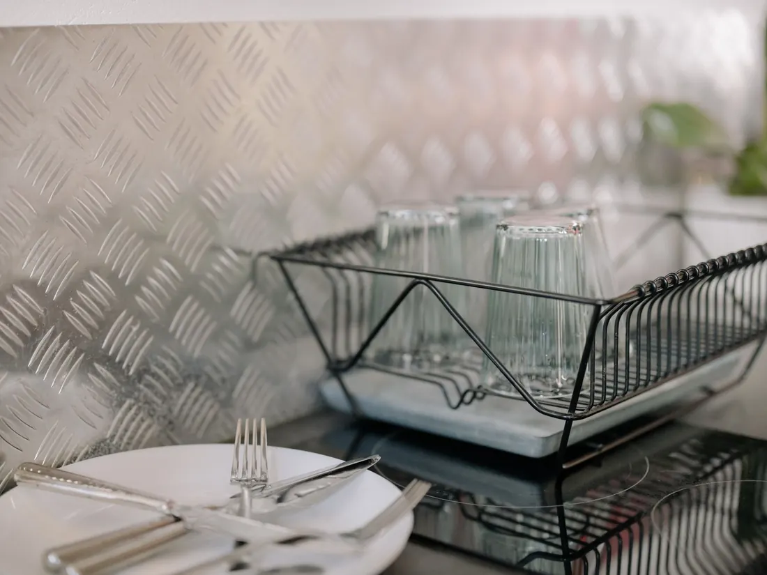 A steel wire dish rack holding glassware in a kitchen