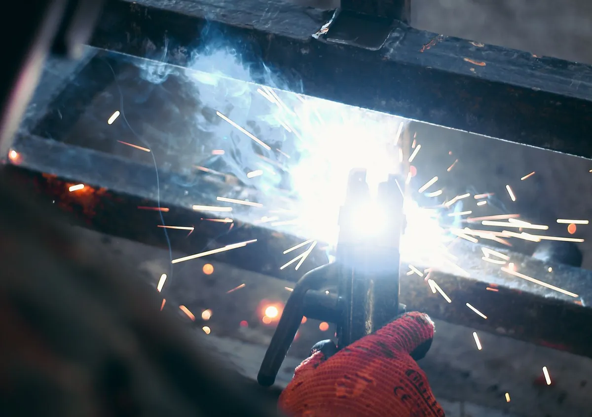 A welder joining steel bars in a workshop