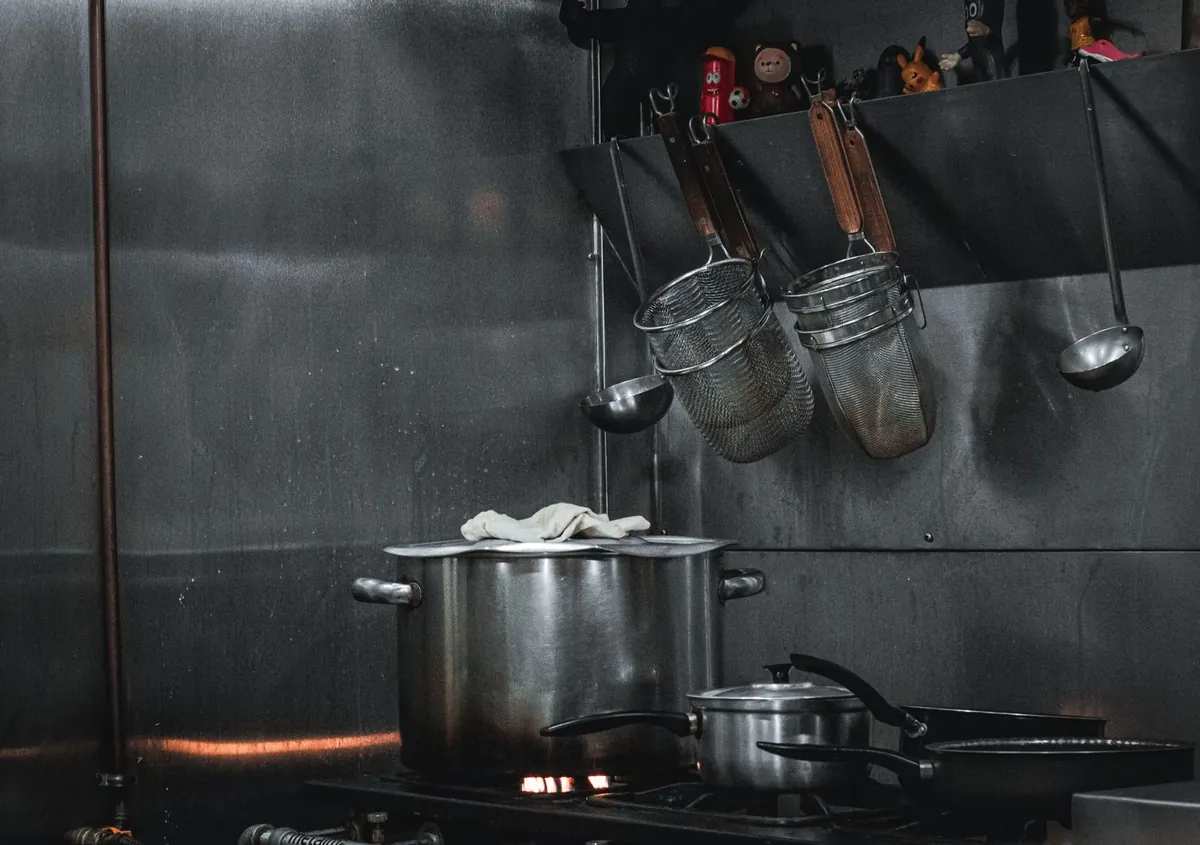 Steel utensils hanging on a rail in a commercial kitchen